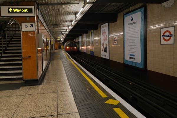 Capture of an underground train approaching at a London Tube station. Iconic signage adds to the urban scene.